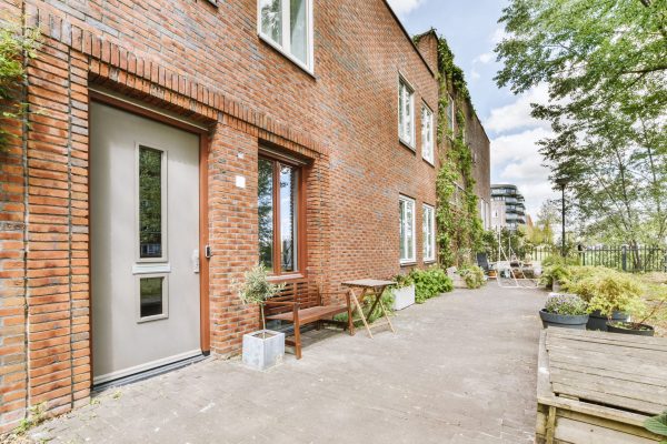 Facade of a residential brick house with doors and windows and sidewalks made of tiles
