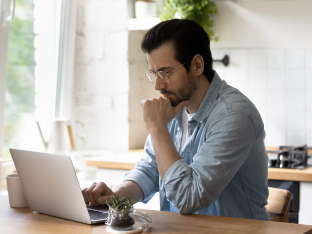 man zit achter laptop